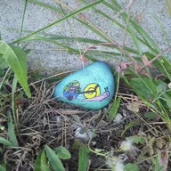 Un escargot bleu au sourire coquin porte sa petite maison jaune sur le dos. Il se cache dans l’herbe, tout près du béton. Tu le vois ? 🐌