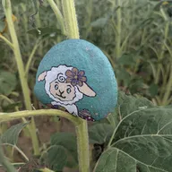 Indice : Un gentil mouton turquoise avec une fleur violette sur la tête. Il se cache parmi les plantes vertes dans le jardin. Tu le trouves ?