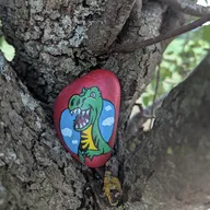 Un drôle de dinosaure rouge s’est blotti dans le creux d’un arbre. Regarde entre les branches, là où l’écorce forme une petite cachette naturelle… il t’attend peut-être juste sous ton nez ! 🌳